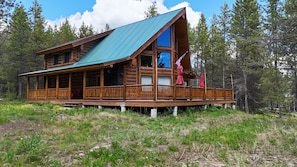 A log cabin with a green roof, wooden deck, and a porch with railings. - The Rocking G - Vacation and recreation by Yellowstone Park (Fremont County)