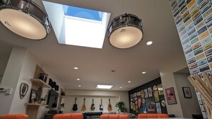 A modern living room with a large window, ceiling lights, a marble coffee table, orange sofas, and guitars on the wall. - Prime Downtown Music Lovers Experience! Nostalgic Mid-Mod In Historic St Peter (Saint Peter)