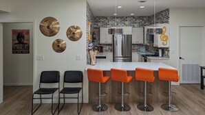 A modern kitchen with a central island, bar stools, and a decorative wall with musical elements. - Prime Downtown Music Lovers Experience! Nostalgic Mid-Mod In Historic St Peter (Saint Peter)