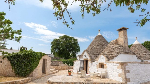 A traditional stone building with a tiled roof, a stone pathway, and a seating area with a table and chairs. - Trulli Bellavista Pool - Cocolic... (Cocolicchio)