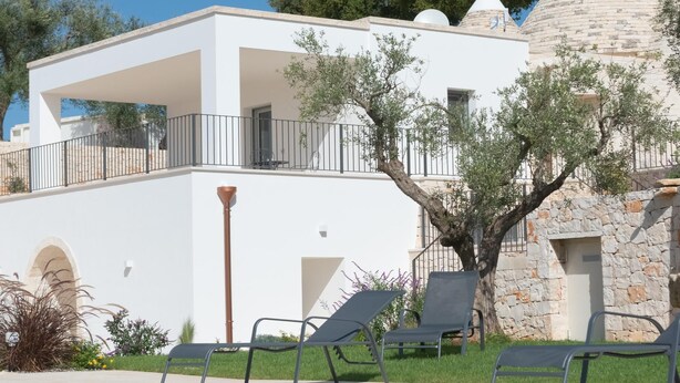 A two-story building with a pool, outdoor seating, and a stone tower. - Trullo Dei Ricordi - Cisternino (Cisternino)
