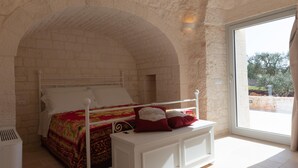 A bedroom with a white bed, red and gold bedding, and a white nightstand. - Trullo Dei Ricordi - Cisternino (Cisternino)