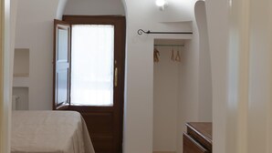 Une chambre à coucher comprenant un lit, une commode, une armoire et une porte donnant sur une autre pièce.
