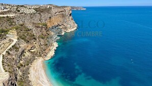 Eine Küstenlandschaft mit freiem Blick auf das Meer, felsigem Gelände und einer Straße, die zum Strand führt.