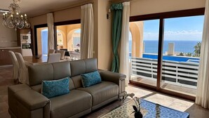 Ein Wohnzimmer mit einer Couch, einem Couchtisch und Blick aufs Meer.