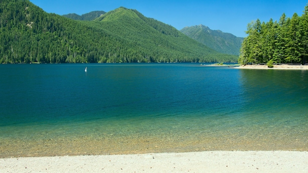 Un lago cristalino rodeado de montañas boscosas.