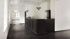 A long, dark wooden bar area with a white tiled backsplash and a hanging light fixture.