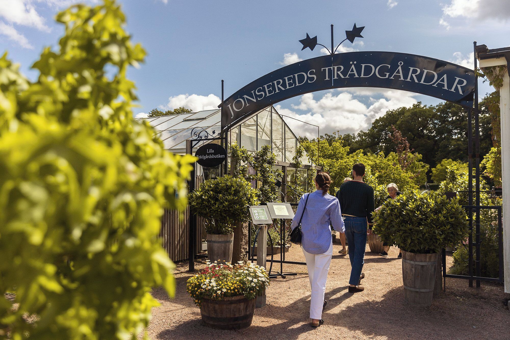 A greenhouse entrance with a sign reading "Lilla Trädgårdsbutiken".