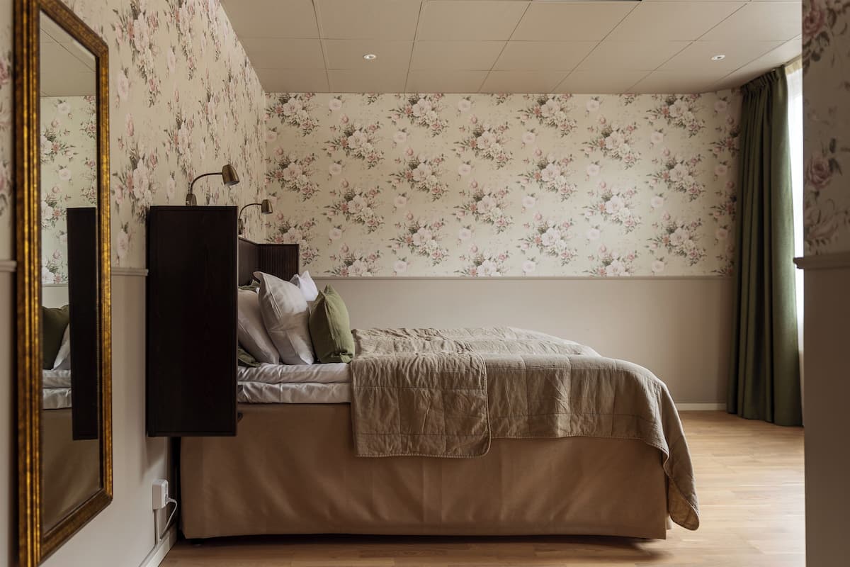 Une chambre à coucher avec un lit, un miroir et un papier peint à motifs floraux.