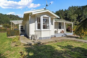 A single-story house with a covered porch, a satellite dish, and a small air conditioning unit.