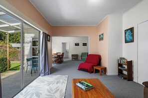 Una sala de estar con comedor, un sofá rojo, una mesa de centro de madera y una estantería.