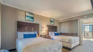 Quarto de hotel com duas camas, varanda e um quadro na parede.