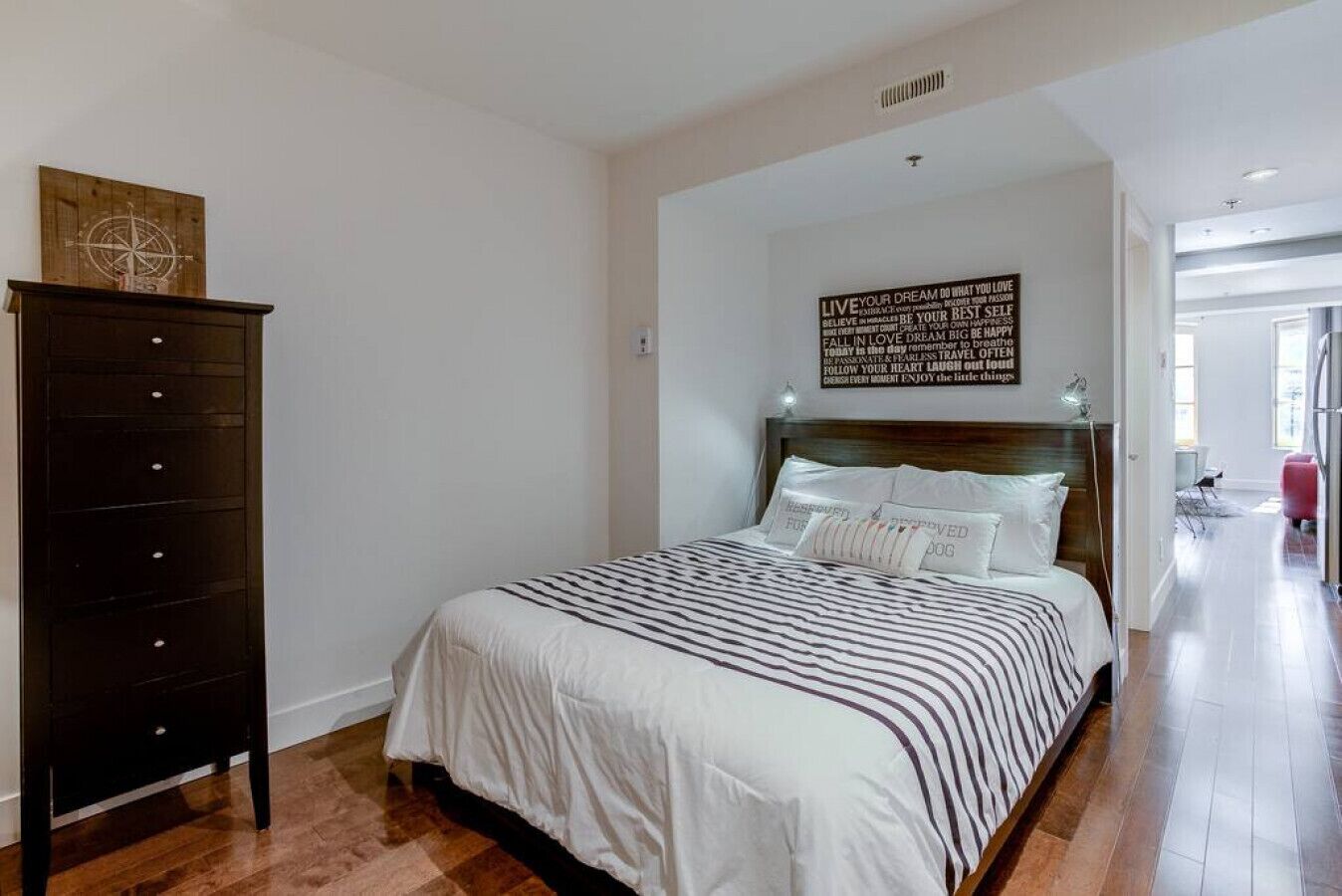 A bedroom with a bed, a dresser, and a motivational quote on the wall.