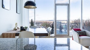 Ein modernes Wohnzimmer mit Essbereich, großen Fenstern und Blick auf die Stadt.
