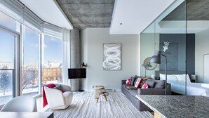 Ein modernes Wohnzimmer mit einem großen Fenster, einem Flachbildfernseher, einer Couch mit Kissen, einem Couchtisch und einer Marmorarbeitsplatte.