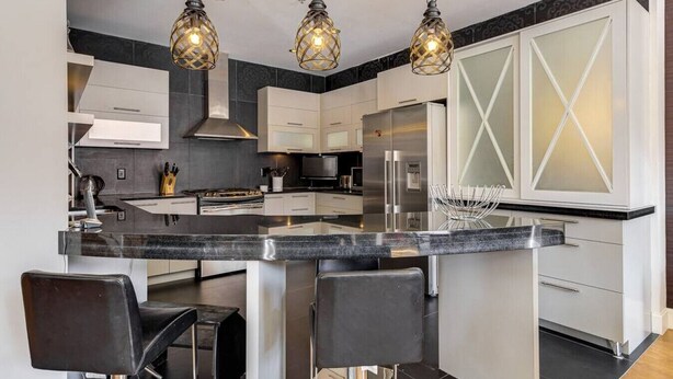 A modern kitchen with a central island, stainless steel appliances, and pendant lighting.