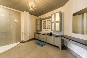 A modern bathroom with a glass shower, a large mirror, and a dark countertop.