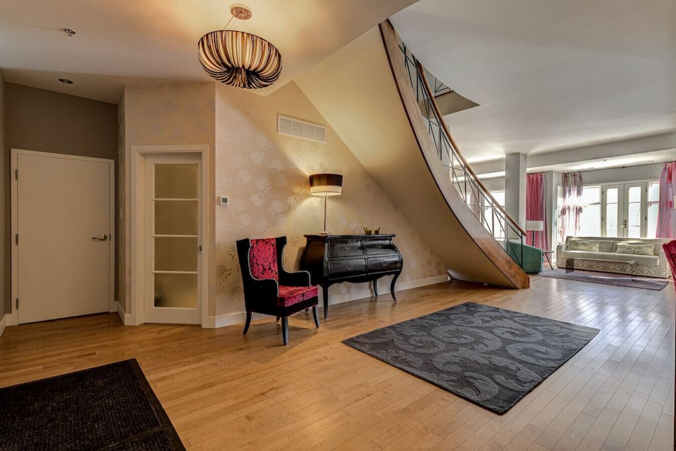 Un'ampia zona giorno con una scala, un pianoforte e una poltrona.