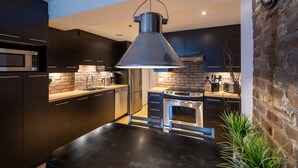 A modern kitchen with dark cabinets, a central island, and a hanging pendant light.