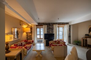 A living room with a sofa, a table, a TV, and a stone wall.