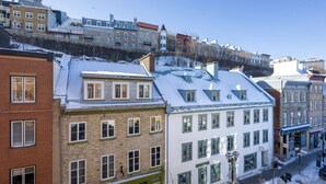 Una hilera de edificios de varios pisos con nieve en los techos, una calle con una farola y un cielo despejado.