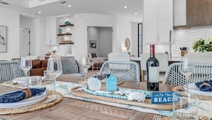 A dining area with a wooden table set for six, featuring a decorative centerpiece and a bottle of wine.