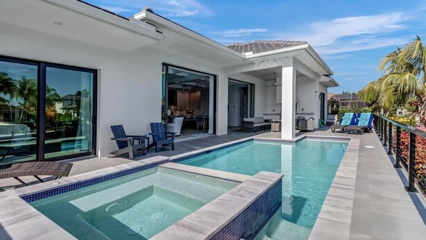 A modern house with a swimming pool, outdoor seating, and a covered patio area.