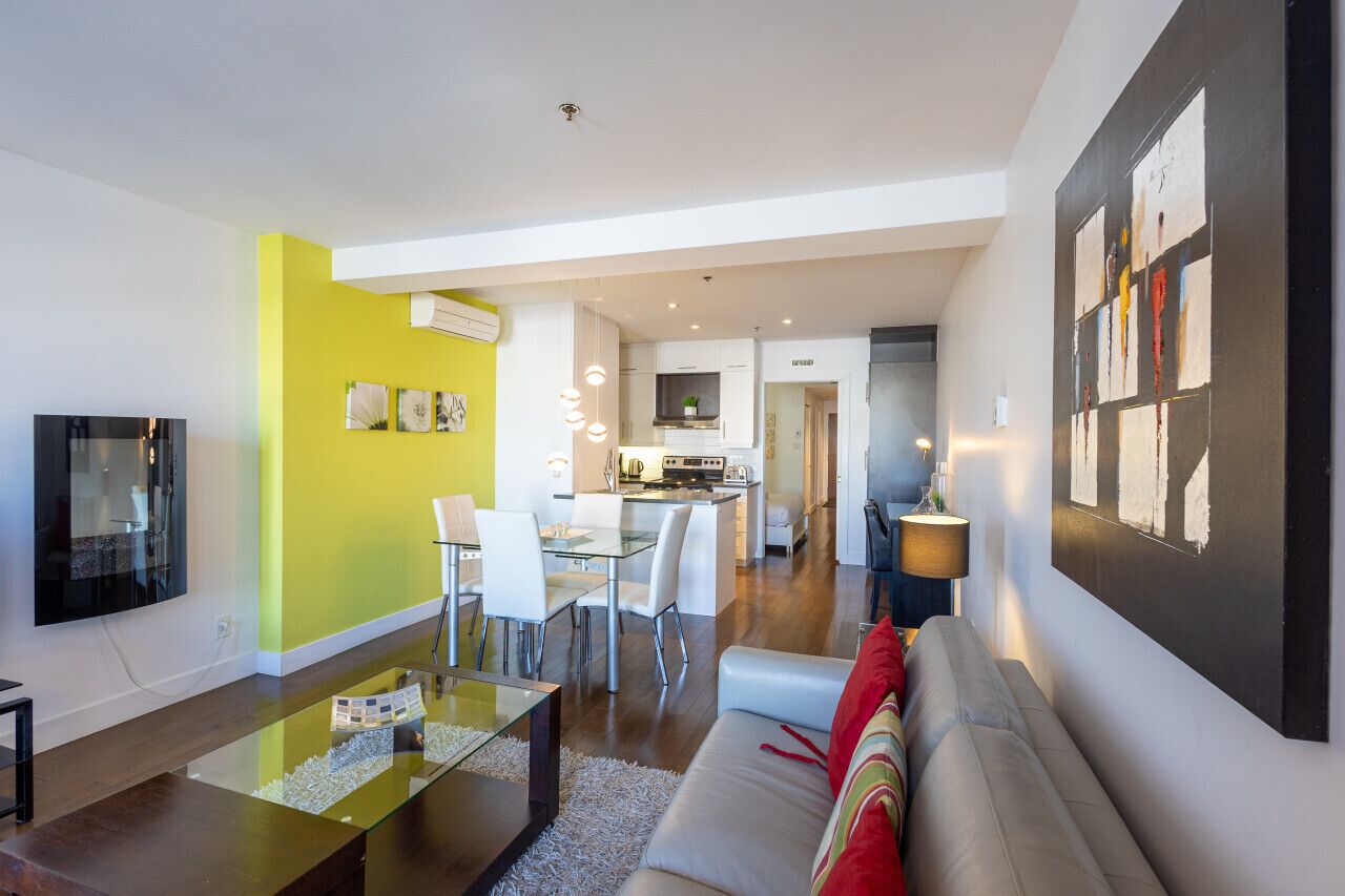 A modern apartment with a dining area, kitchen, and living room.
