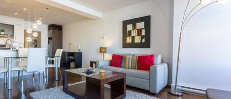 A modern living room with a sofa, coffee table, and dining area.