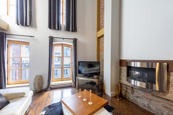 Ein modernes Wohnzimmer mit Sofa, Couchtisch, Fernseher und Kamin.