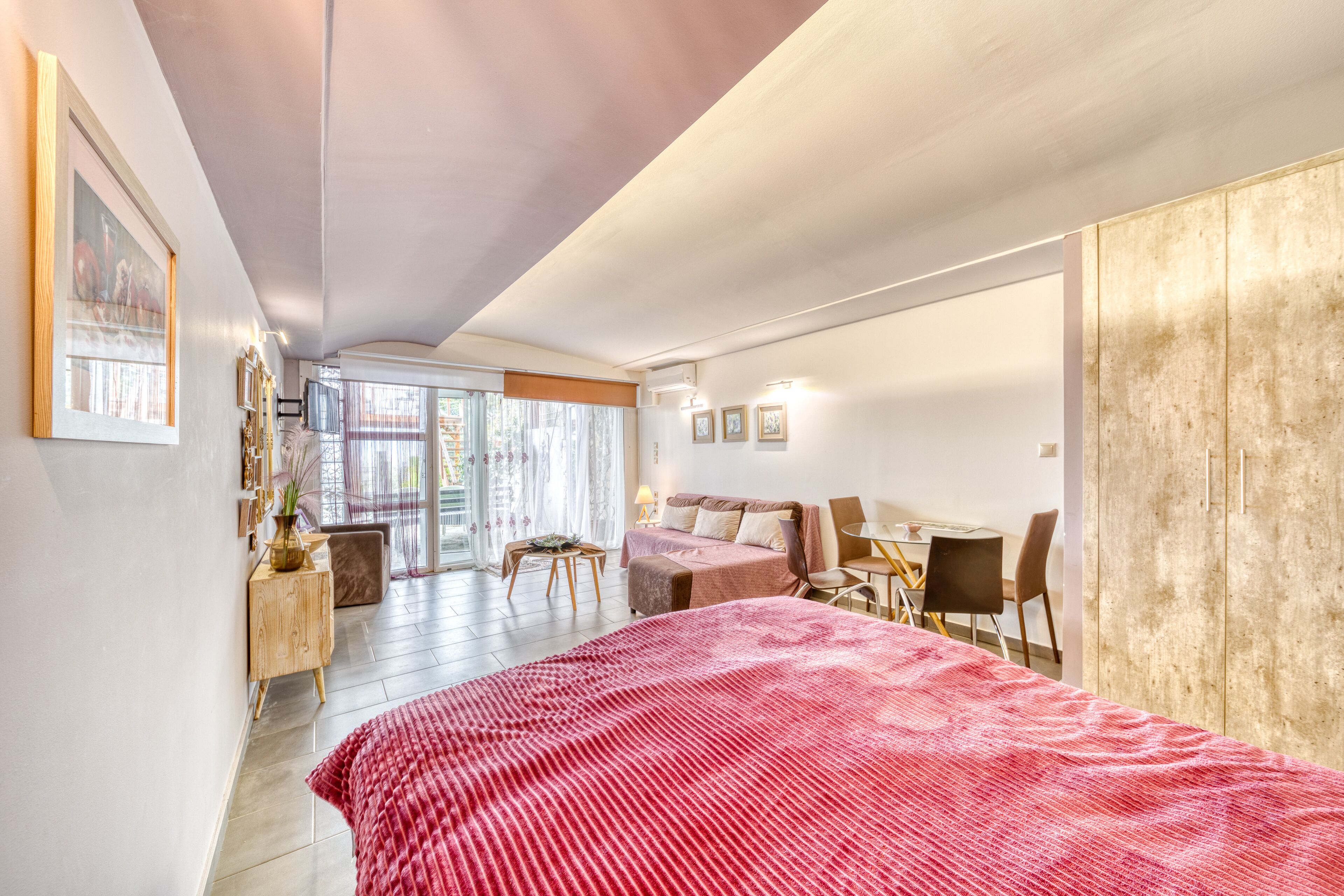 Een moderne slaapkamer met een groot bed, een houten kledingkast, een bureau en een bank.