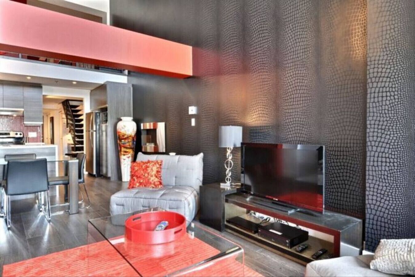 Un salon moderne avec un canapé, un téléviseur et des touches de couleur rouge.