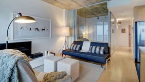 A modern living room with a sofa, a coffee table, a TV, and a lamp. - Les Immeubles Charlevoix - 760214 (Ville de Québec)