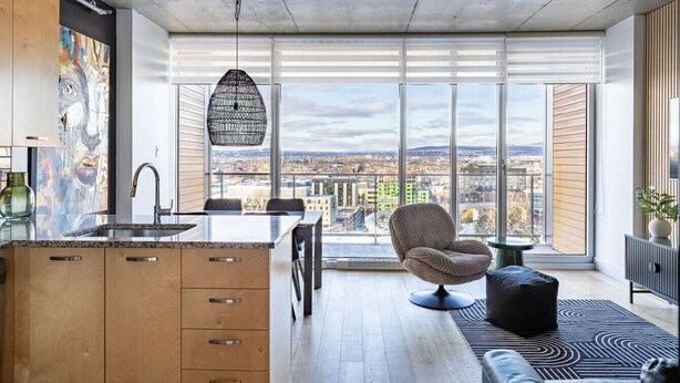 A modern kitchen with a large window, a hanging light fixture, and a city view.