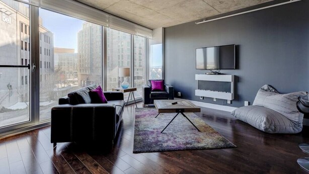 Un salon moderne avec une grande fenêtre, un téléviseur à écran plat, un canapé, une table basse et un tapis.