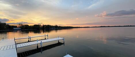 Un lago tranquilo al atardecer con un muelle de madera que se adentra en el agua.