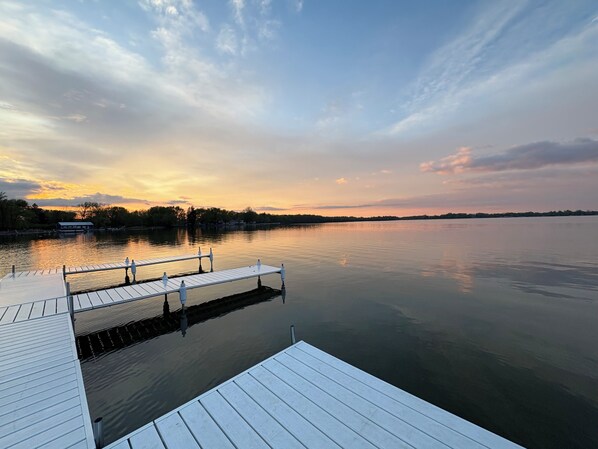 Un lac paisible au coucher du soleil, avec une jetée en bois qui s’avance sur l’eau.