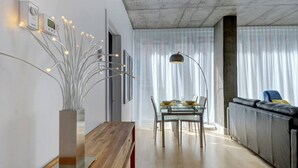 Ein modernes Wohnzimmer mit Essbereich, ausgestattet mit einem Glastisch, einer Holzbank und einer zeitgemäßen Leuchte.