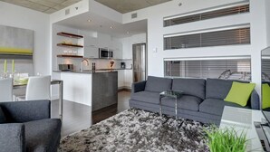 A modern living room with a grey sofa, a glass coffee table, and a fluffy rug. - Les Immeubles Charlevoix - 760431 (Ville de Québec)