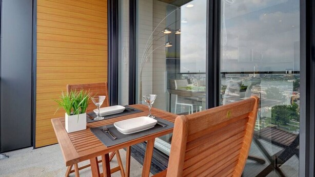 A modern dining area with a wooden table and chairs, a potted plant, and a glass partition. - Les Immeubles Charlevoix - 760431 (Ville de Québec)