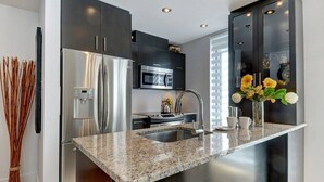 Una cocina moderna con electrodomésticos de acero inoxidable, encimera de granito y armarios oscuros.