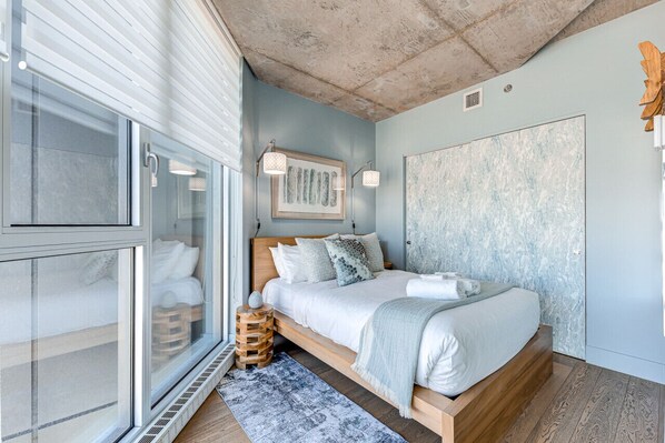 Un dormitorio con cama, ventana y un cuadro abstracto grande.