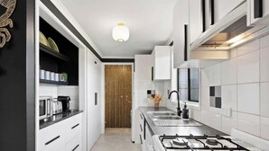 A modern kitchen with white cabinetry, a gas stove, and a wooden door.