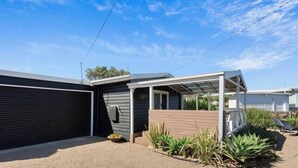 A modern house with a garage, a covered patio, and a garden with plants.