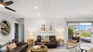 A modern living room with a sofa, armchairs, a coffee table, and artwork on the walls.
