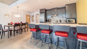 Una cocina moderna con taburetes de bar, una mesa de comedor y una lámpara colgante.