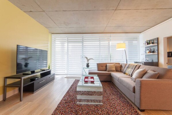 Una sala de estar moderna con un sofá, televisor y una mesa de centro.