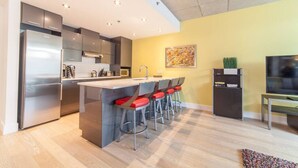 Una cocina moderna con una isla central, electrodomésticos de acero inoxidable y una zona de comedor con taburetes de bar.