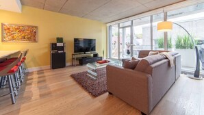 Una sala de estar moderna con un sofá, televisión y comedor.
