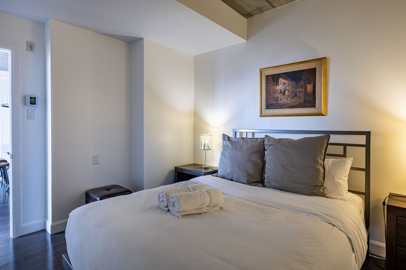 Une chambre d’hôtel avec un grand lit, une table de chevet, une lampe de chevet et un tableau au mur.